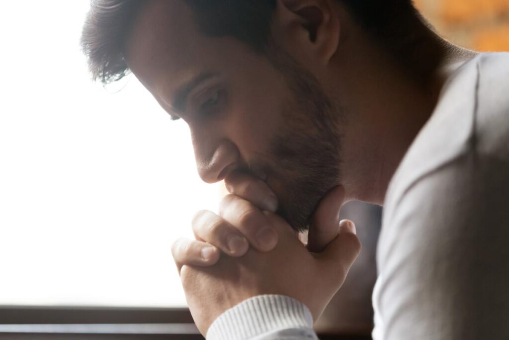 a man leans his head down to rest on his palms and is thinking about what is secret drinking