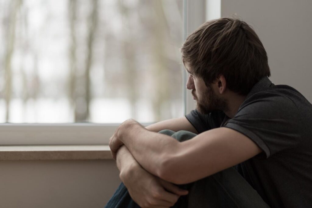 person pensively looking out window while struggling with cocaine dependence