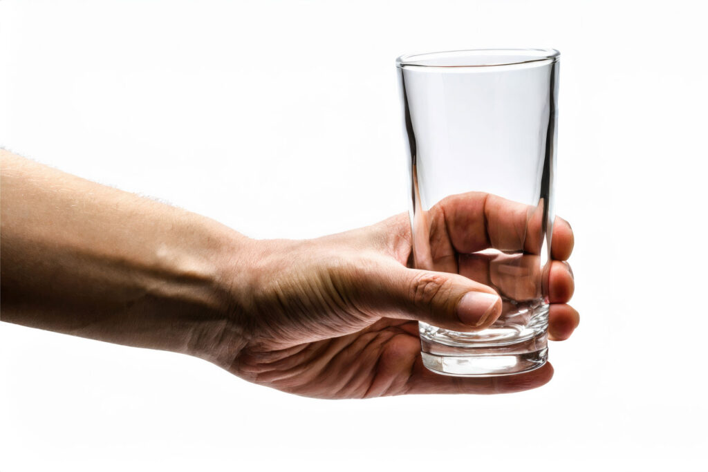 A hand holds an empty glass waiting to be filled with alcohol. They will mix Adderall and alcohol.