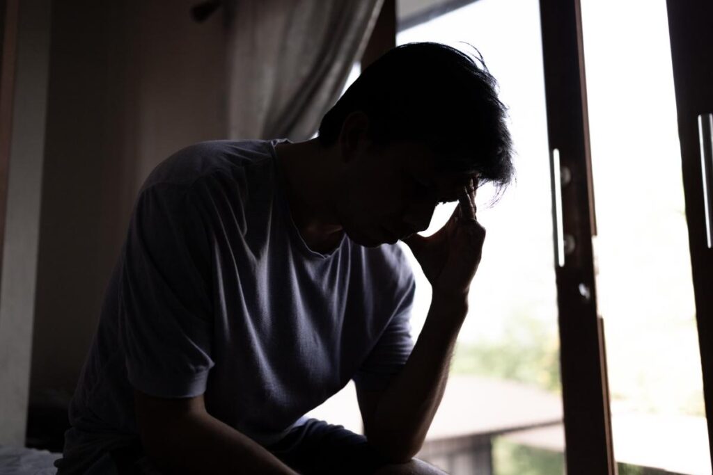 A man sits in the dark and is experiencing the effects of cocaine abuse.