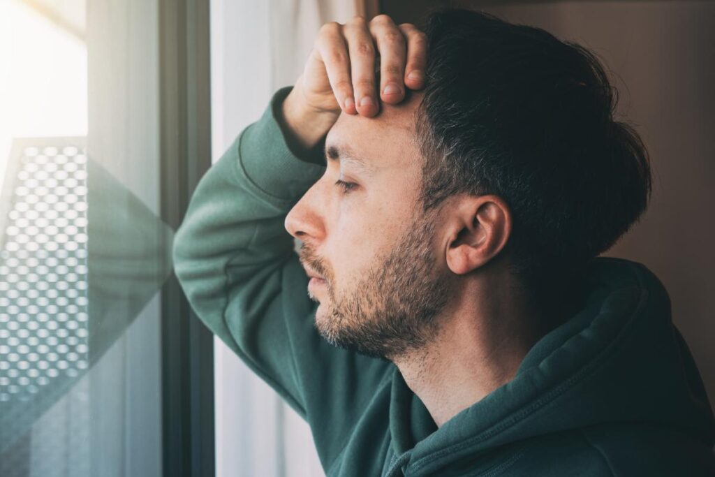 A man experiencing high functioning depression, looks out the window.