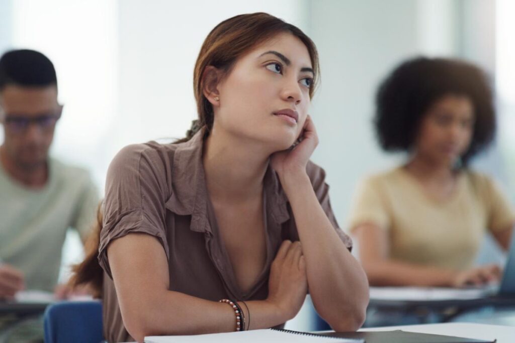 A woman is experiencing the symptoms of ADHD while trying to focus in class.