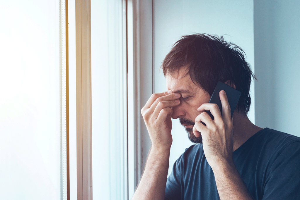 A man is experiencing the signs of fentanyl use. He's pinching the bridge of his nose and making a phone call.