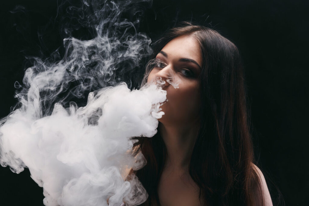 young woman exhaling a cloud of white vapor while explaining what is galaxy gas